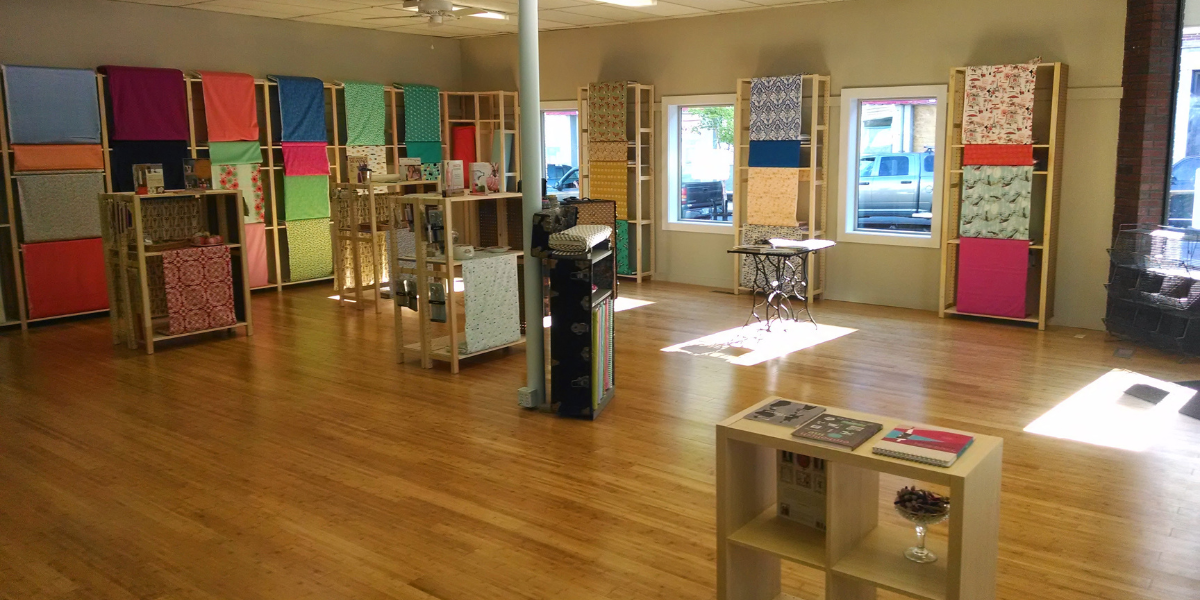 Colorful fabrics displayed in a sewing store in Rockland, ME with wood floors and large windows looking out onto Maine Street.